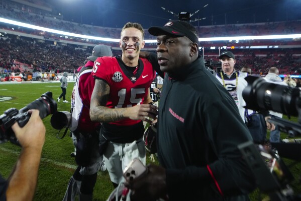 Georgia quarterback Carson Beck (15) and assistant coach Josh Crawford run off the field after defeating Tennessee in an NCAA college football game, Saturday, Nov. 16, 2024, in Athens, Ga. (AP Photo/John Bazemore)