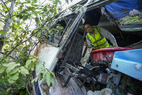 A forensic official inspects a bus that fell into a deep gorge on Sunday after being fired at by suspected militants in Reasi district, Jammu and Kashmir, Monday, June 10, 2024. The bus was carrying pilgrims to the base camp of the famed Hindu temple Mata Vaishno Devi when it came under attack killing at least nine people. (AP Photo/Channi Anand)