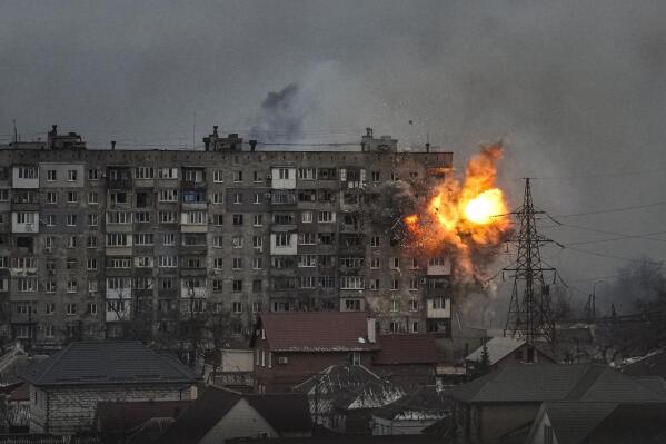 An explosion erupts from an apartment building at 110 Mytropolytska St., after a Russian army tank fired on it in Mariupol, Ukraine, Friday, March 11, 2022. On the seventh floor of the building, two elderly women Lydya and Nataliya were stuck in their apartment because they couldn't make it down to the shelter, and were killed in the explosion. The two heavily burned bodies were buried by neighbors in front of the building. (AP Photo/Evgeniy Maloletka)