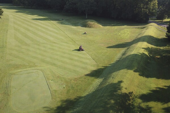 FILE - A groundskeeper mows near the flat-topped mound that is part of the 50-acre octagon at Moundbuilders Country Club at the Octagon Earthworks in Newark, Ohio, July 30, 2019. A trial was slated to begin Tuesday, May 28, 2024, to determine how much the historical society must pay for the ancient ceremonial and burial earthworks, which is among eight ancient areas in the Hopewell Earthworks system named a World Heritage Site last year. (Doral Chenoweth III/The Columbus Dispatch via AP, File)