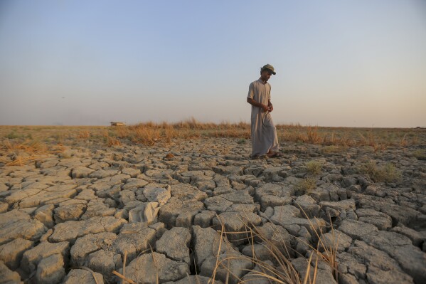 FIEL - A fisherman walks across a dry patch of land in the marshes in Dhi Qar province, Iraq, Sept. 2, 2022. The three-year drought that has left millions of people in Syria, Iraq and Iran with little water wouldn’t have happened without human-caused climate change, according to a new study on Wednesday, Nov. 8, 2023. (AP Photo/Anmar Khalil, File)