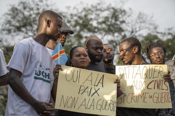 People gather in Goma, Democratic Republic of the Congo, Monday, May 6, 2024, to mourn the victims of the Mugunga Camp attack three days earlier. The signs read: 'Yes to peace, No to war' and 'Attacking civilians is a war crime.' (AP Photo/Moses Sawasawa)