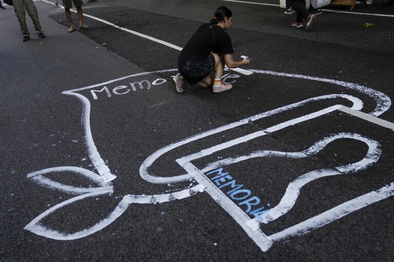 A demonstrator paints silhouettes representing the people who disappeared during the 1976-1983 military dictatorship, during a march marking the 48th anniversary of the coup in Buenos Aires. (AP Photo/Rodrigo Abd)