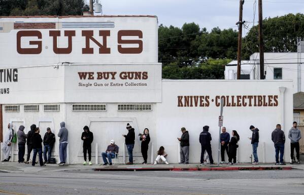 FILE - In this March 15, 2020 file photo people wait in a line to enter a gun store in Culver City, Calif. The 9th U.S. Circuit Court of Appeals on Thursday, Jan. 20, 2022, overturned two California counties orders shutting down gun and ammunition stores in 2020 as nonessential businesses during the coronavirus pandemic. (AP Photo/Ringo H.W. Chiu, File)