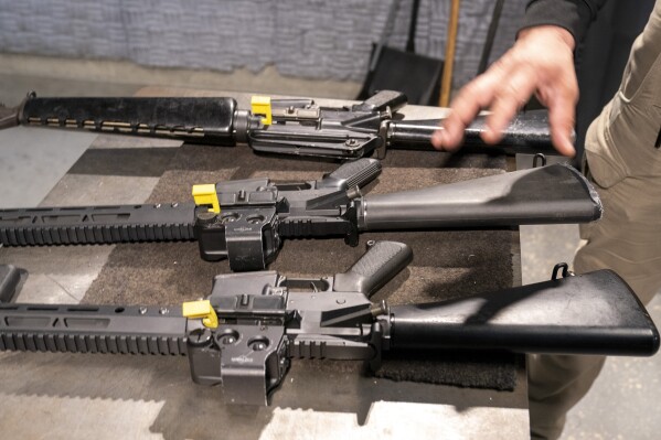 A row of AR-15 style rifles is displayed for a photograph, one with a conversion device installed making it fully automatic, and one a fully automatic M-16 machine gun, at the Bureau of Alcohol, Tobacco, Firearms, and Explosives (ATF), National Services Center, Thursday, March 2, 2023, in Martinsburg, W.Va. Machine guns have been illegal in the U.S. for decades, but in recent years the country has seen a new surge of weapons capable of automatic fire. Small pieces of plastic or metal used to convert legal guns into homemade machine guns are helping to fuel gun violence. (AP Photo/Alex Brandon)