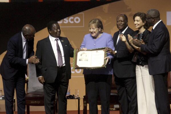 Former German Chancellor Angela Merkel, center right, receives the Felix Houphouet Boigny price in Yamoussoukro, Ivory Coast, Wednesday Feb. 8, 2023. Merkel has been honored with the UNESCO peace prize for her efforts to allow more than 1.2 million migrants between 2015-2016 into Germany. (AP Photo/Diomande Ble Blonde)