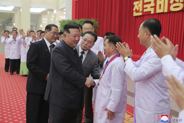 In this photo provided by the North Korean government, North Korean leader Kim Jong Un shakes hands with a health official in Pyongyang, North Korea, Wednesday, Aug. 10, 2022. Kim has declared victory over COVID-19 and ordered an easing of preventive measures. Independent journalists were not given access to cover the event depicted in this image distributed by the North Korean government. The content of this image is as provided and cannot be independently verified. Korean language watermark on image as provided by source reads: "KCNA" which is the abbreviation for Korean Central News Agency. (Korean Central News Agency/Korea News Service via AP)