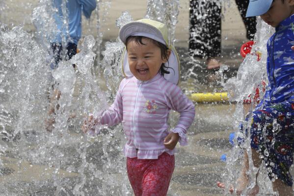 Children play in the water to cool off at a park in Yokohama, near Tokyo, Tuesday, Aug. 18, 2020. The number of babies born in Japan in 2022 is below last year’s record low in what the the top government spokesman described as a “critical situation.” (AP Photo/Koji Sasahara)