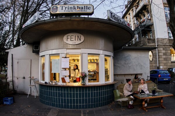 People sit at a former water house, a small shop that sprung up in the 19th century to encourage workers to drink affordable water rather than beer or schnapps, that is now a cafe in Frankfurt, Germany, on March 17, 2025. (AP Photo/Michael Probst)
