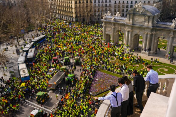 People look at a farmers' protest in Madrid, Spain, Wednesday, Jan. 21, 2024. Hundreds of farmers drove their tractors into central Madrid on Wednesday as part of ongoing protests against European Union and local farming policies and to demand measures to alleviate production cost hikes. (AP Photo/Manu Fernandez)