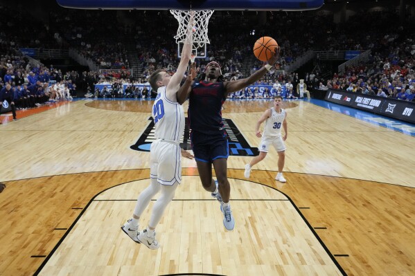 Duquesne guard Jimmy Clark III (1) shoots under BYU guard Spencer Johnson (20) in the second half of a first-round college basketball game in the NCAA Tournament, Thursday, March 21, 2024, in Omaha, Neb. (AP Photo/Charlie Neibergall)