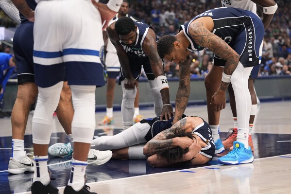 Dallas Mavericks center Dereck Lively II (2) is checked on by teammates after a head injury during the first half in Game 3 of the NBA basketball Western Conference finals against the Minnesota Timberwolves, Sunday, May 26, 2024, in Dallas. (AP Photo/Julio Cortez)