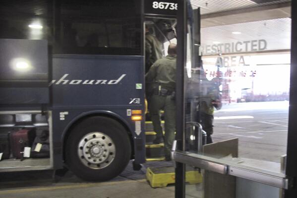 FILE - In this Thursday, Feb. 13, 2020 file photo, agents for Customs and Border Protection board a Greyhound bus headed for Portland, Ore., at the Spokane Intermodal Center, a terminal for buses and Amtrak, in Spokane, Wash. Greyhound Lines Inc. will pay $2.2 million to settle a lawsuit over the bus line's practice of allowing U.S. Customs & Border Protection agents to board its buses in Washington state to conduct warrantless immigration sweeps, the state attorney general said Monday, Sept. 27, 2021. (AP Photo/Nicholas K. Geranios, File)