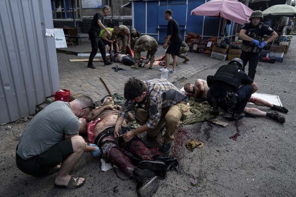 EDS NOTE: GRAPHIC CONTENT - Paramedics give first aid to injured people at the food market after Russian shelling attack in the city center of Kostiantynivka, Ukraine, Wednesday, Sept. 6, 2023. Dozens of people were killed and dozens more wounded Wednesday when Russian shelling struck a market in a city in eastern Ukraine, officials said. (AP Photo/Evgeniy Maloletka)