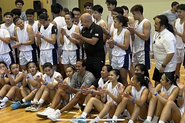 Miami Heat coach and USA Basketball assistant Erik Spoelstra, seated at center, poses with campers and clinic staff after a basketball clinic in Manila, Philippines, Wednesday, Aug. 22, 2023. Spoelstra, whose mother hails from the Philippines, is back there for the first time in 11 years. The U.S. plays its World Cup opener there on Saturday. (AP Photo/Tim Reynolds)