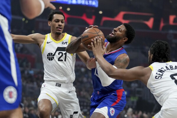 Los Angeles Clippers forward Paul George drives to the basket against Utah Jazz forward Darius Bazley (21) and forward Brice Sensabaugh during the first half of an NBA basketball game in Los Angeles, Friday, April 12, 2024. (AP Photo/Eric Thayer)