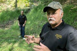FILE-This Sept. 20, 2018 file photo, Dennis Parada, right, and his son Kem Parada stand at the site of the FBI's dig for Civil War-era gold in Dents Run, Pennsylvania. Government emails released under court order show that FBI agents were looking for gold when they excavated Dent's Run in 2018, though the FBI says that nothing was found. (AP Photo/Michael Rubinkam, File)