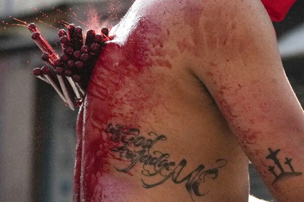 A Filipino penitent flagellates himself as part of Maundy Thursday rituals to atone for sins or fulfill vows for an answered prayer on April 6, 2023 at Mandaluyong city, Philippines. (AP Photo/Aaron Favila)