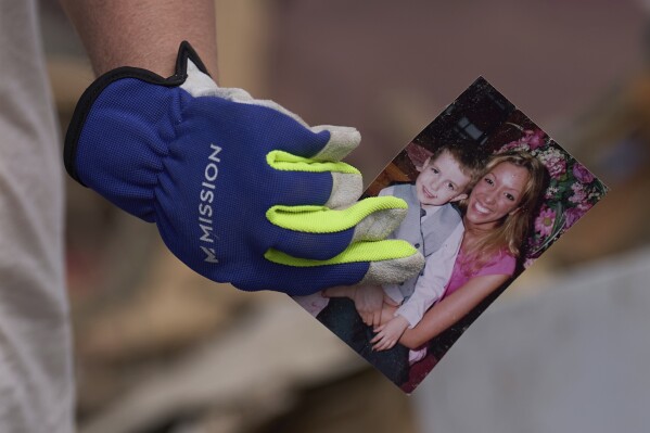 Edwina Wilson holding photos she recovered on Sunday, May 18, 2025, from the ruins of her destroyed home in London, Kentucky, after a violent storm passed through the region. (AP Photo/Caroline Custer)