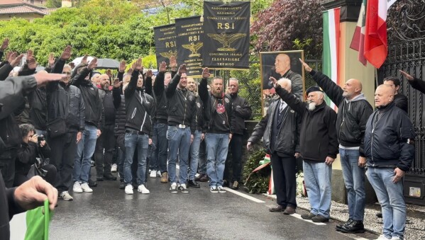 Dozens of people raise their arms in the fascist salute and shout the fascist chant "present" in Dongo, northern Italy, Sunday, April 28, 2024 during ceremonies to honor Italian dictator Benito Mussolini on the 79th anniversary of his execution. Dressed in black, the neo-fascist supporters marched through northern Italian towns where Mussolini was arrested and executed at the end of World War II. (LaPresse Via AP)