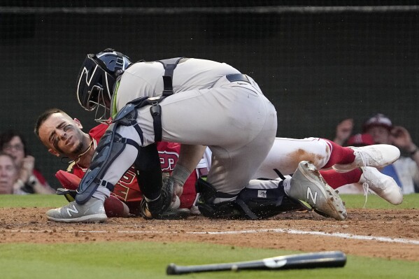 Los Angeles Angels' Zach Neto, left, winces after colliding with New York Yankees catcher Jose Trevino as he tried to score on a double by Shohei Ohtani during the third inning of a baseball game Monday, July 17, 2023, in Anaheim, Calif. Neto was tagged out on the play. (AP Photo/Mark J. Terrill)