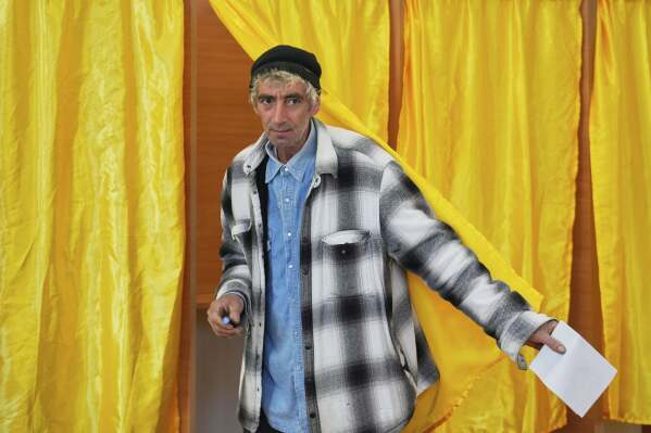 A man exits a voting cabin before casting his vote in the first round of the presidential election redo in Mogosoaia, Romania, Sunday, May 4, 2025. (AP Photo/Vadim Ghirda)