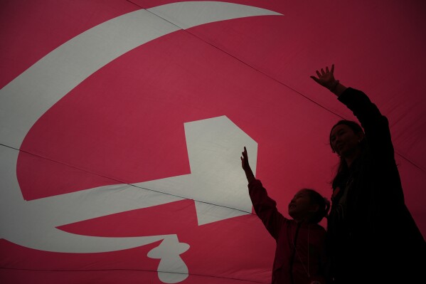 People walk under the giant Victory Banner unfolded at the WWII open-air museum at the Red Square in Moscow, Russia, Saturday, June 21, 2025, ahead of the 80th anniversary of the 1945 Victory Parade. (AP Photo/Pavel Bednyakov)