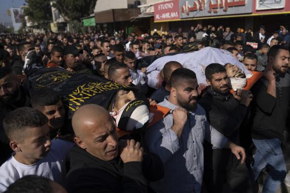 Palestinian mourners carry the bodies of Naeem Jamal Zubaidi, 27, left and Mohammad Ayman Saadi, 26, covered with flags of the Islamic Jihad Movement, during their funeral in the West Bank city of Jenin, Thursday, Dec. 1, 2022. Israeli forces killed Zubaidi and Saadi during an arrest raid Thursday in the occupied West Bank, according to the Israeli military and the Islamic Jihad militant group, the latest bloodshed in months of violence between the sides. (AP Photo/Nasser Nasser)
