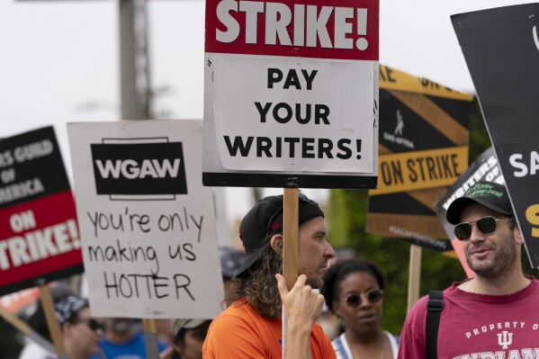 Demonstrators hold signs during a rally outside the Paramount Pictures Studio in Los Angeles, Thursday, Sept. 21, 2023. Negotiations between striking screenwriters and Hollywood studios have resumed and will continue Thursday, the latest attempt to bring an end to pickets that have brought film and television productions to a halt. (AP Photo/Jae C. Hong)