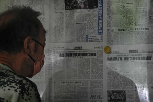 A man reads a Global Times newspaper carrying an article, center, that reads "U.S has resisted strong skepticism about restricting investment in China" posted on a public newspaper bulletin board in Beijing, Thursday, Aug. 10, 2023. China accused Washington on Thursday of trying to block its development after President Joe Biden stepped up a feud over technology and security by tightening controls on U.S. investments that might help Beijing develop its military. (AP Photo/Andy Wong)