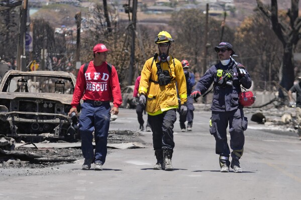 Members of a search-and-rescue team walk along a street, Saturday, Aug. 12, 2023, in Lahaina, Hawaii, following heavy damage caused by wildfire. (AP Photo/Rick Bowmer)