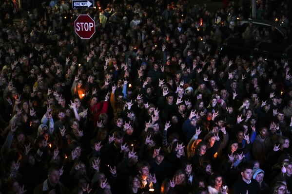 FILE - People sign "I love you" while gathered at a vigil for the victims of Wednesday's mass shootings, Oct. 29, 2023, outside the Basilica of Saints Peter and Paul in Lewiston, Maine. A commission investigating the shooting that killed 18 people is scheduled to hear from a police agency that had contact with the shooter before he committed the killings. Maine Gov. Janet Mills and Attorney General Aaron Frey assembled the commission to review the events that led up to the shootings at a bowling alley and a restaurant in Lewiston on Oct. 25. The commission, which is holding its second meeting Thursday, Jan/ 25, 2024 is also tasked with reviewing the police response to the shootings. (AP Photo/Matt Rourke, file)