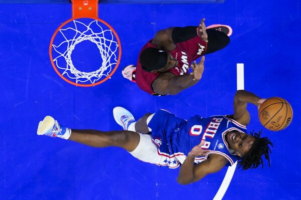 Philadelphia 76ers' Tyrese Maxey (0) goes up to shoot against Miami Heat's Bam Adebayo, top, during the first half of an NBA basketball game, Monday, March 18, 2024, in Philadelphia. (AP Photo/Matt Rourke)