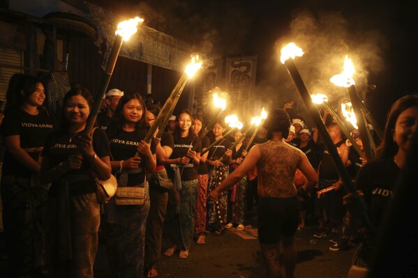 Balinese women carry bamboo torches as they participate in an Ogoh-ogoh parade as part of Balinese Hindu New Year celebrations, in Bali, Indonesia on Sunday, March 10, 2024. (AP Photo/Firdia Lisnawati)