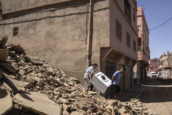 Dos personas recuperan una lavadora de su casa dañada por un sismo en la localidad de Amizmiz, cerca de Marrakech, Marruecos, el domingo 10 de septiembre de 2023. Soldados marroquíes y equipos de ayuda en camiones y helicópteros trataban de llegar a localidades remotas de montaña devastadas por un enorme terremoto que mató a más de 2.400 personas, mientras sobrevivientes desesperados buscaban ayuda para ayudar a seres queridos que temían se hubieran quedado atrapados bajo los escombros. (AP Foto/Mosa'ab Elshamy)
