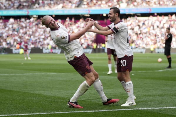 Manchester City's Erling Haaland, left, celebrates with Bernardo Silva after scoring his side's third goal during the English Premier League soccer match between West Ham United and Manchester City at London stadium in London, Saturday, Sept. 16, 2023. (AP Photo/Kin Cheung)