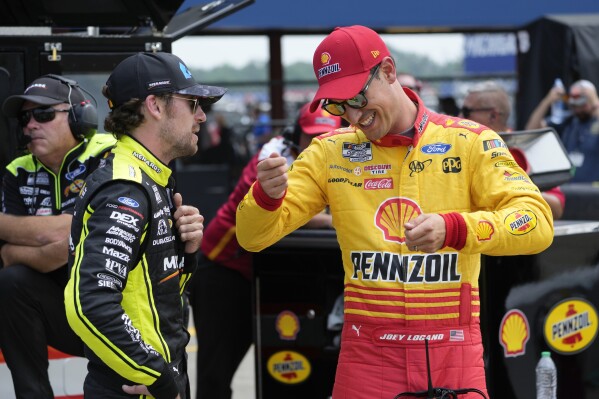 Ryan Blaney, left, and Joey Logano talk during qualifications for a NASCAR Cup Series auto race at Michigan International Speedway in Brooklyn, Mich., Saturday, Aug. 5, 2023. (AP Photo/Paul Sancya)