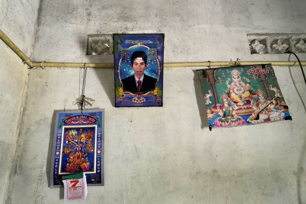 A portrait of Parasuraman Thulasiyamma's missing son is displayed with the pictures of Hindu deities inside their home in Mullaitivu, Sri Lanka, Tuesday, May 7, 2024. Sri Lanka's civil war, which pitted Sri Lankan government forces against Tamil Tiger separatists, ended 15 years ago but many people are still searching for children or other family members who are missing, some presumed dead. (AP Photo/Eranga Jayawardena)