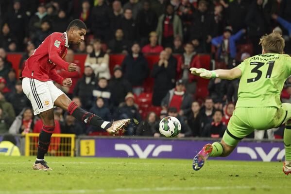 Manchester United's Marcus Rashford, left, scores his side's third goal past Charlton's goalkeeper Ashley Maynard-Brewer during the English League Cup quarter final soccer match between Manchester United and Charlton Athletic at Old Trafford in Manchester, England, Tuesday, Jan. 10, 2023. (AP Photo/Dave Thompson)