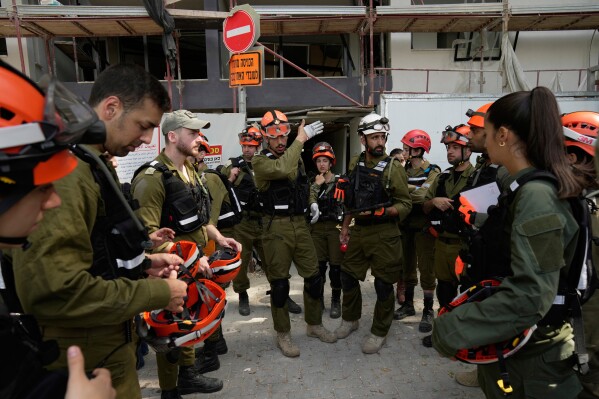 Israeli soldiers from the Home Front Command gather at the site of an Iranian missile strike in Tel Aviv, Israel, Sunday, June 22, 2025. (AP Photo/Bernat Armangue)