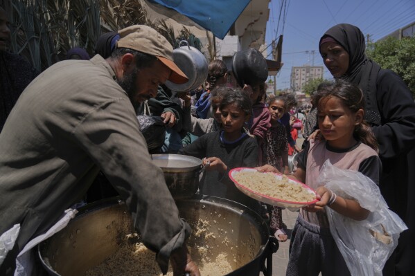 Palestinian children get food at a food distribution kitchen in Deir al-Balah, Gaza Strip, Friday, May 30, 2025. (AP Photo/Abdel Kareem Hana)