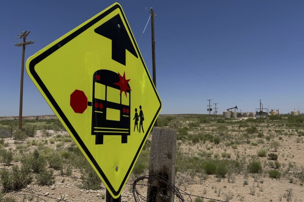 A sign warns drivers of a school bus stop near an oilfield, on the outskirts of Loving, N.M., on Tuesday, May 19, 2025. (AP Photo/Susan Montoya Bryan)