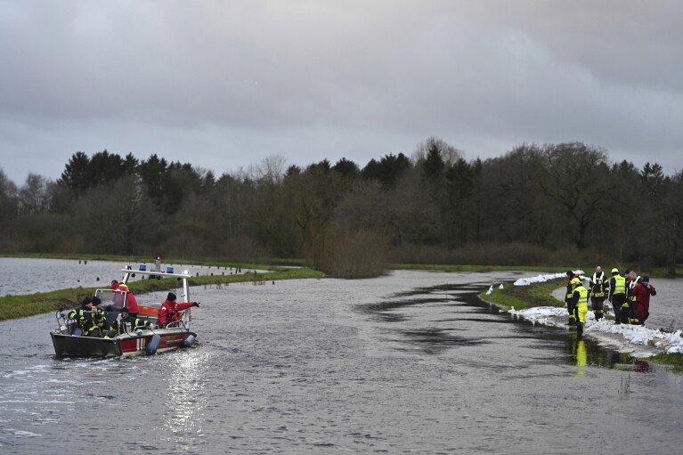 Firefighters try to secure the area from floodwaters from the Burlage-Langholter Tief, a tributary of the Leda, after it overflowed, in Langholt, Germany, Tuesday, Dec. 26, 2023. Firefighters and volunteers labored to reinforce dikes against rising floodwaters in northern and eastern Germany as heavy rains falling on already soaked ground pushed rivers and streams over their banks and forced several towns to evacuate residents. (Lars Penning/dpa via AP)