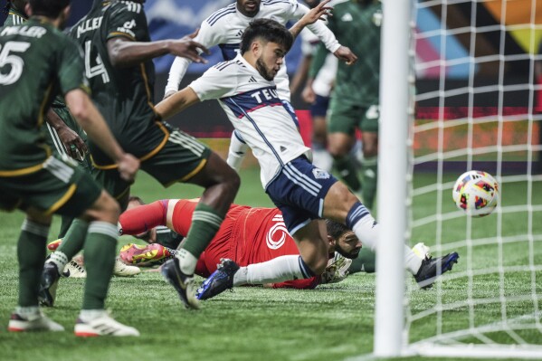 Portland Timbers goalkeeper Maxime Crepeau, back center, watches as Vancouver Whitecaps' Ryan Raposo scores during the second half of an MLS soccer match, in Vancouver, British Columbia, on Saturday, March 30, 2024. (Darryl Dyck/The Canadian Press via AP)