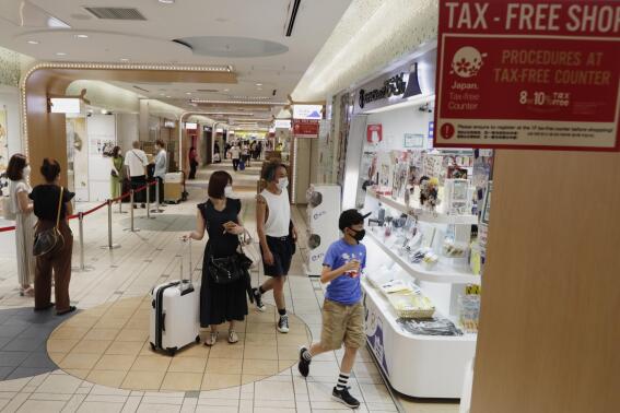 FILE - Shoppers walk into a store at a shopping center in Tokyo on Aug. 17, 2020. The Japanese economy has contracted at an annual rate of 1.2% in the July-September quarter, as consumption declined amid rising prices. (AP Photo/Hiro Komae, File)
