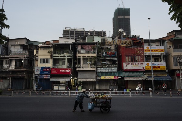A fruit vendor pushes her cart along the street as buildings under construction are seen in the distance in Ho Chi Minh City, Vietnam, Jan. 12, 2024. (AP Photo/Jae C. Hong)