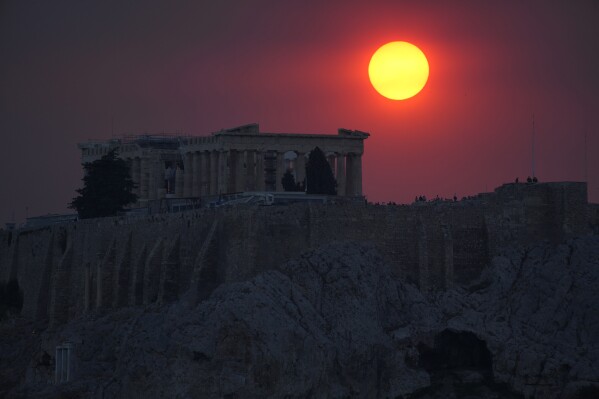 Smoke from a wildfire on the outskirts of the Greek capital covers the sun as it sets over the Parthenon temple atop of the ancient Acropolis in Athens, Aug. 22, 2023. (AP Photo/Thanassis Stavrakis)