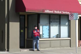 FILE - A volunteer escort outside Affiliated Medical Services, a Milwaukee abortion clinic, on Wednesday, May 28, 2014, in Milwaukee. Abortion providers are bracing for the final days of the U.S. Supreme Court's guarantee of a right to an abortion by halting scheduling for the procedure, transitioning staff to help patients travel to other states and creating networks of clinics that will span across regions of the country. Planned Parenthood of Wisconsin, which operates three clinics that provide abortions in the state, is not scheduling the procedure beyond June 25, 2022. (AP Photo/Dinesh Ramde File)
