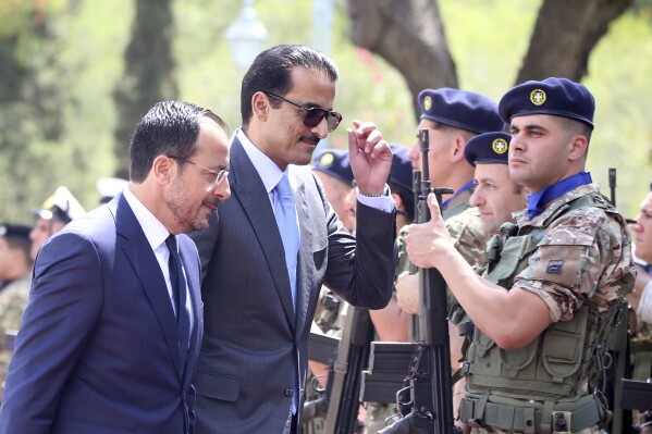 Cyprus' President Nikos Christodoulides, left, and Qatar's Emir Sheikh Tamim bin Hamad al-Thani review a military guard of honor, prior to their meeting at the presidential palace in Nicosia, Cyprus, Tuesday, May 28, 2024. Qatar's Emir is in Cyprus for an official visit. (AP Photo/Philippos Christou)