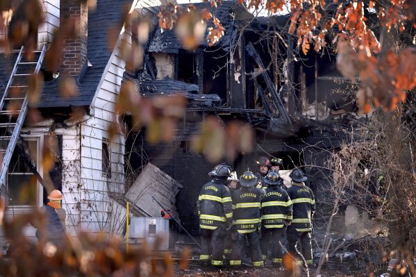 Firefighters gather around a burned out section of a home after they extinguished the flames of house fire on Monday, Feb. 19, 2024 in Ferguson, Mo. A mother and four children died early Monday as police say the fire is being investigated as 